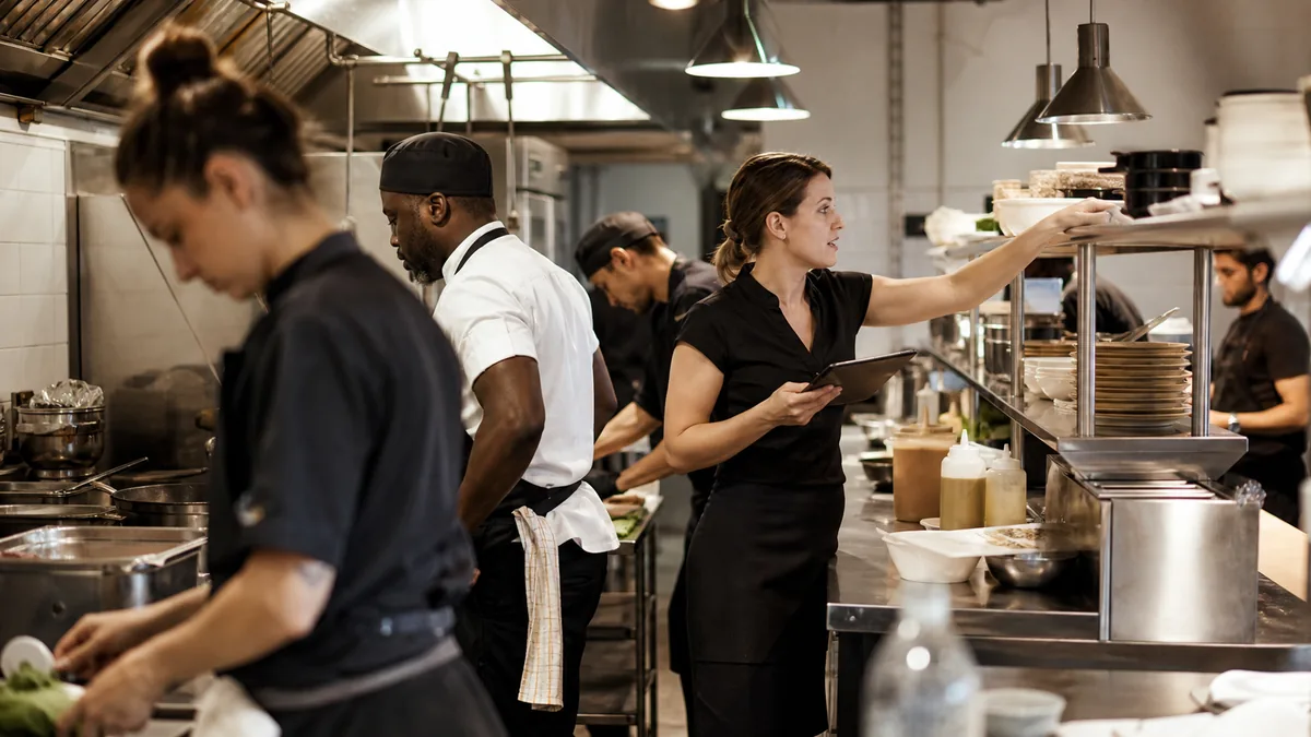Busy restaurant kitchen team working through service